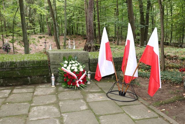 Miejsce pamięci ofiar reżimów totalitarnych - tzw. Lisie Jamy. Zapalone znicze, wieniec i flagi państwowe.
