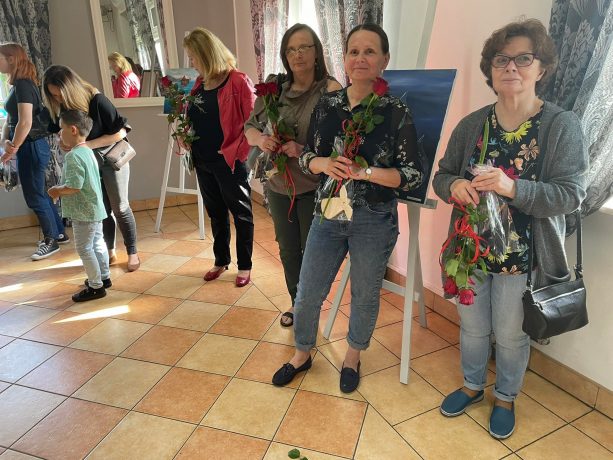 Uczestniczki zajęć stoją w sali wystawy z różami. 